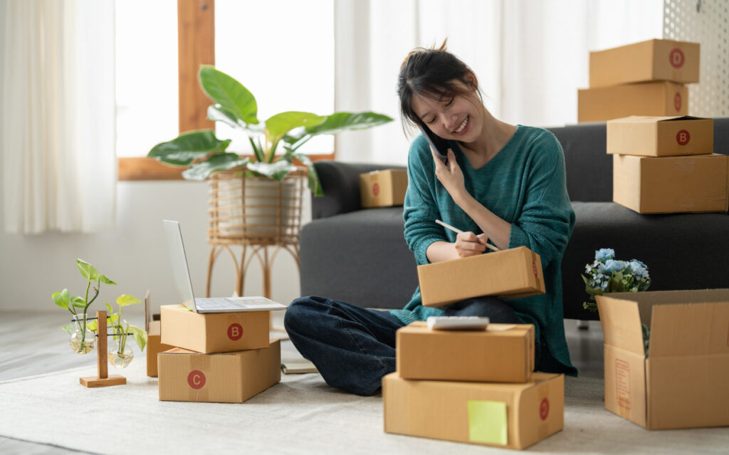 woman sitting and addressing a stack of boxes