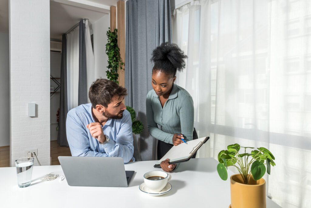 Two business partners working in the office looking and reading statistics at the end of the calendar year on laptop. Businesspeople small company owners using computer for online trade.