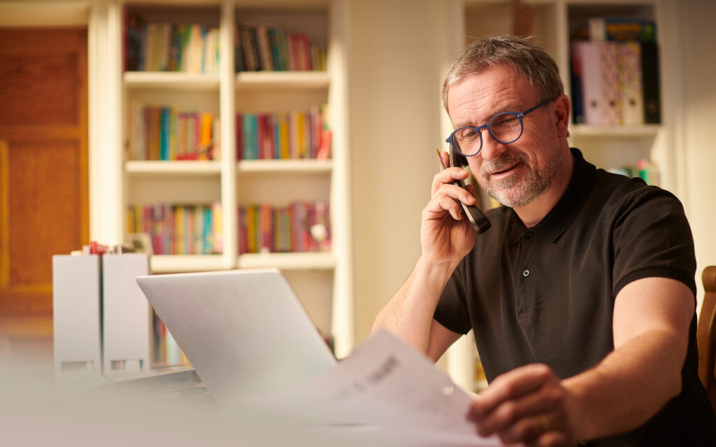 man on his phone looking at paperwork