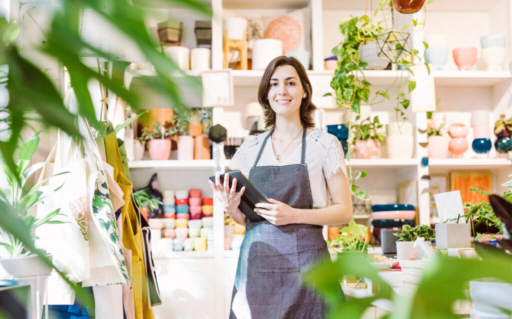 woman in an apron in a store with a tablet collecting transactions