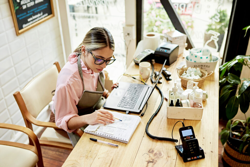 woman at a desk with papers and a laptop crunching numbers