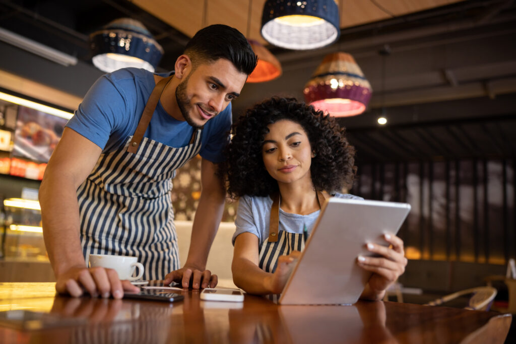 Woman at laptop helping a waiter working at a restaurant