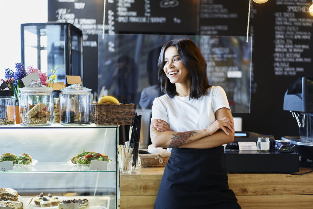 Happy female cafe owner standing.