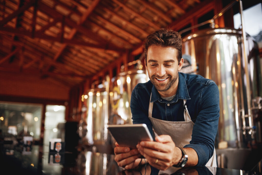 small business browsing on a digital tablet while patiently waiting at the bar for customers inside of his brewery