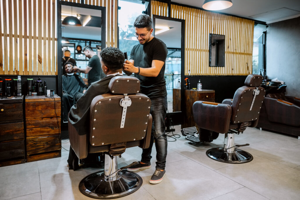 Young professional hairdresser cutting hair of client in salon