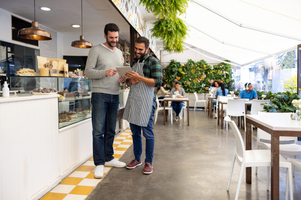 Waiter at a cafe showing a menu to a customer on a tablet computer