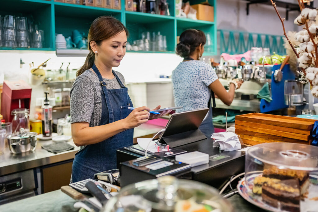 Waitress Checking Bills, Orders and Cash Register with Tablet Computer